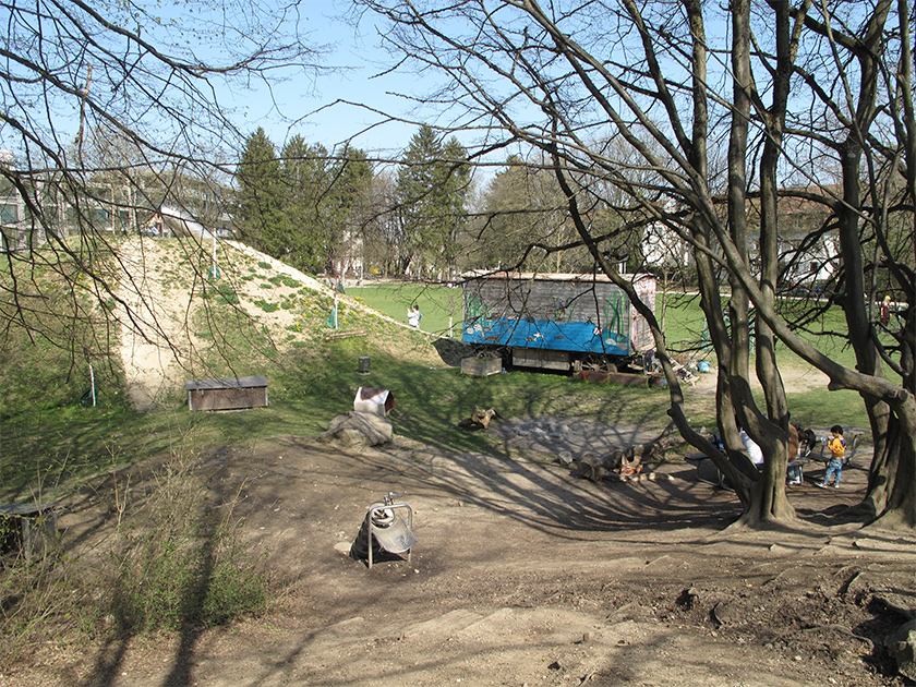 Spielplatz mit Bauwagen und eienm Berg mit Rutsche
